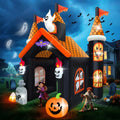 Black haunted house inflatable with orange roofs, ghosts and a pumpkin, kids walking through at night