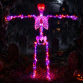 Skeleton outlined in pink and purple LEDs with red eyes standing with arms outstretched at night