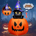 Black cat in a purple witch hat popping out of a jack-o'-lantern inflatable at night