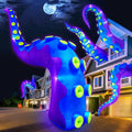 Giant purple octopus tentacle inflatables with neon suckers rising around a house at night