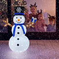 Lighted pop-up snowman in a top hat and blue scarf outside a window with children watching