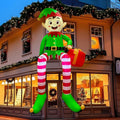 Elf inflatable with striped legs sitting on a shop awning holding a gift