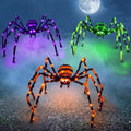 Three large lighted spiders in purple, green and orange on a foggy lawn at night